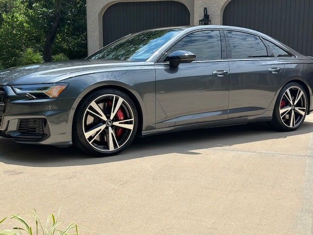 A gray audi a6 is parked in a driveway in front of a garage.