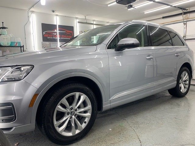 A silver audi q7 is parked in a garage.