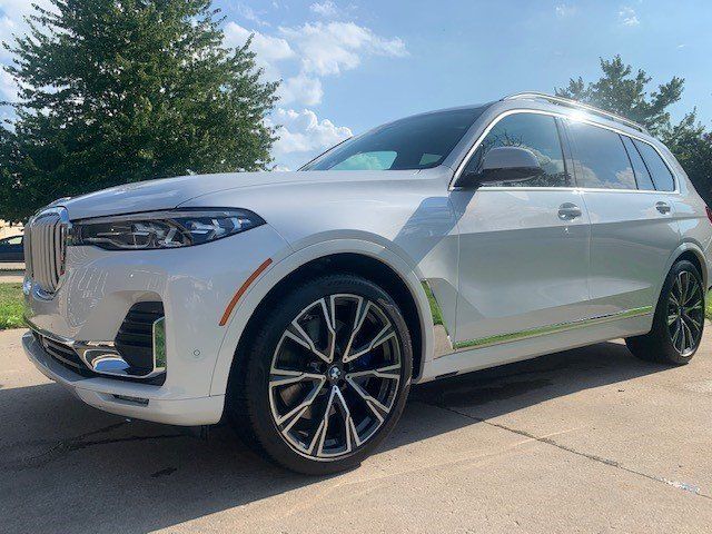 A white bmw x7 is parked on the side of the road.