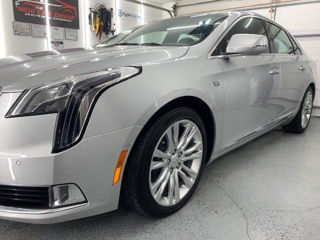 A silver cadillac is parked in a garage.