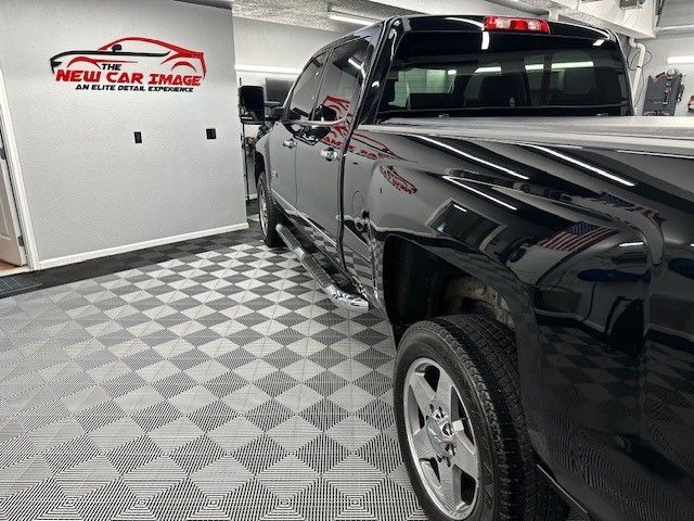 A black truck is parked in front of a wall that says the new car image