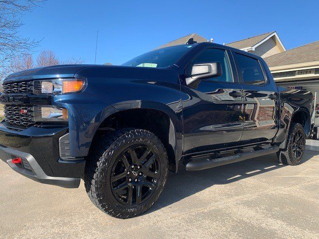 A black truck is parked in a driveway in front of a house.