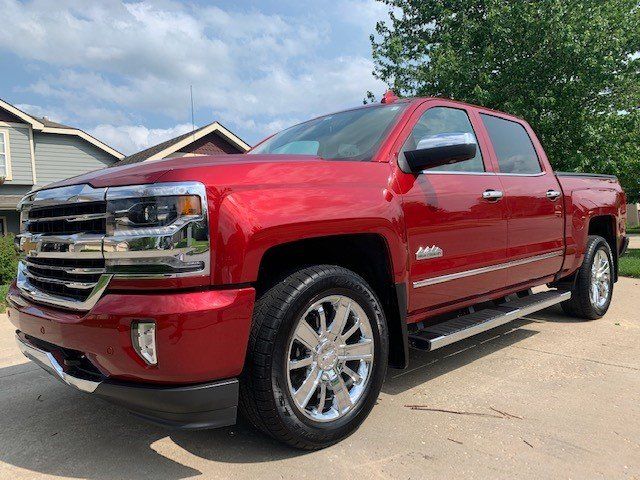 A red truck is parked in a driveway in front of a house.