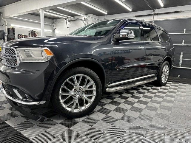 A black dodge durango is parked in a garage on a checkered floor.