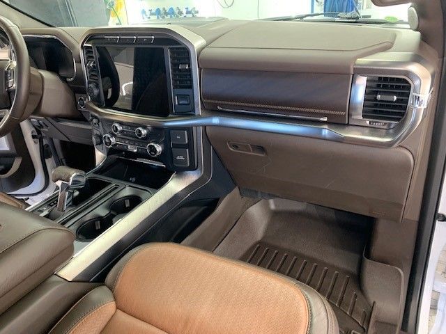 The interior of a white truck with brown seats and a steering wheel.