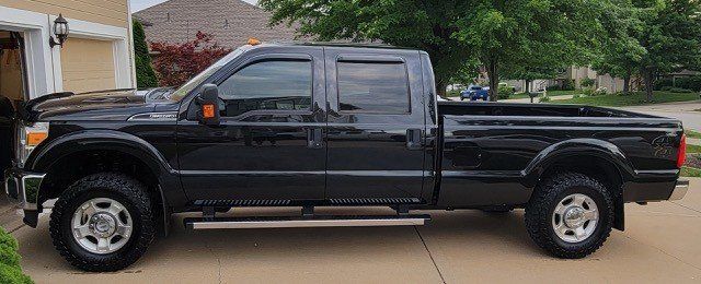 A black pickup truck is parked in a driveway in front of a house.