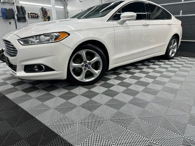 A white ford fusion is parked on a checkered floor in a garage.