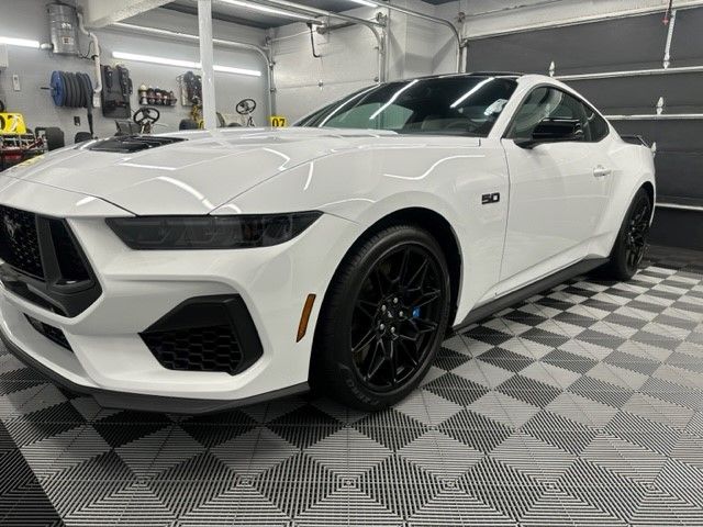 A white ford mustang is parked in a garage.
