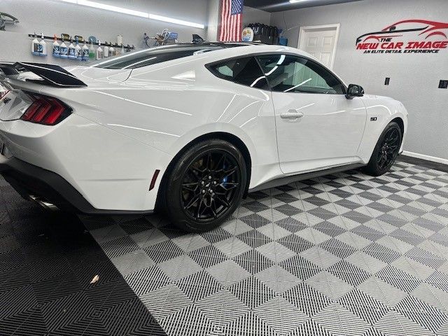 A white ford mustang is parked in a garage.