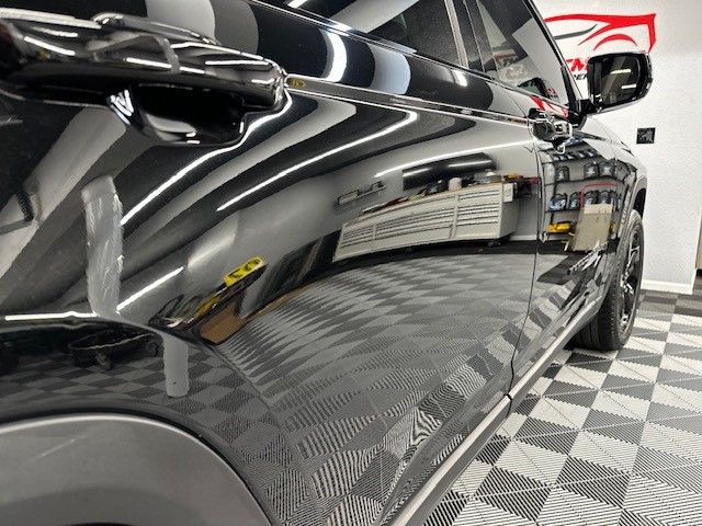 A black car is parked on a checkered floor in a garage.