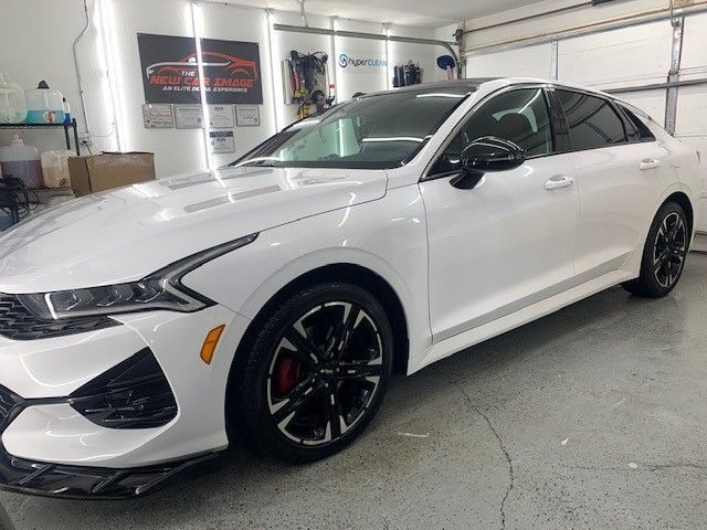A white car is parked in a garage next to a garage door.