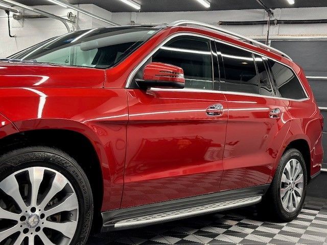 A red mercedes benz gl550 is parked in a garage.