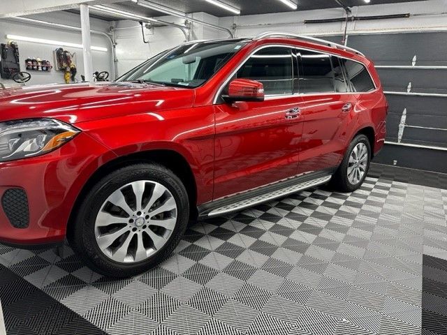 A red suv is parked in a garage on a checkered floor.
