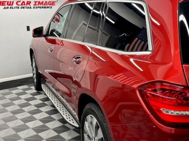 A red car is parked in front of a new car image sign