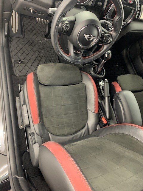 The interior of a mini cooper with a steering wheel and seats.