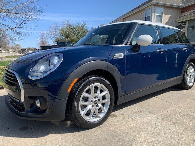 A blue mini cooper clubman is parked in a driveway in front of a house.