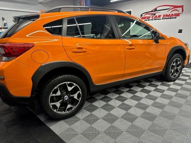 An orange subaru crosstrek is parked in a garage.