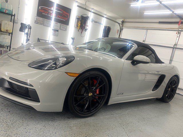 A white porsche boxster is parked in a garage.