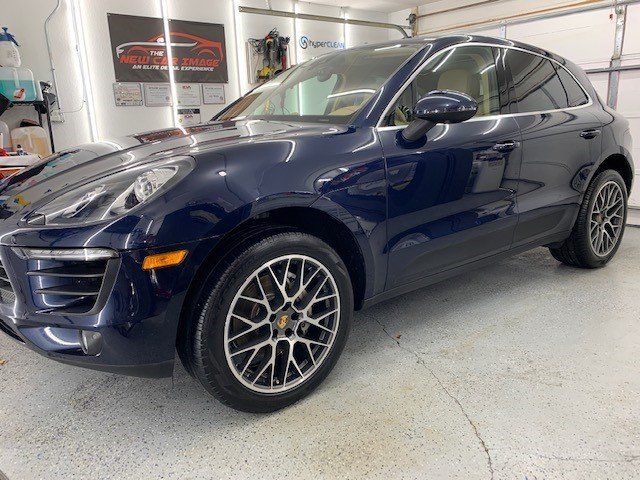 A blue porsche macan is parked in a garage.