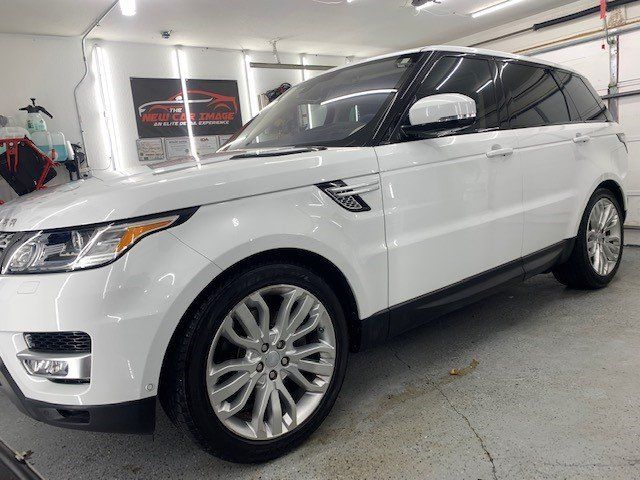 A white range rover sport is parked in a garage.