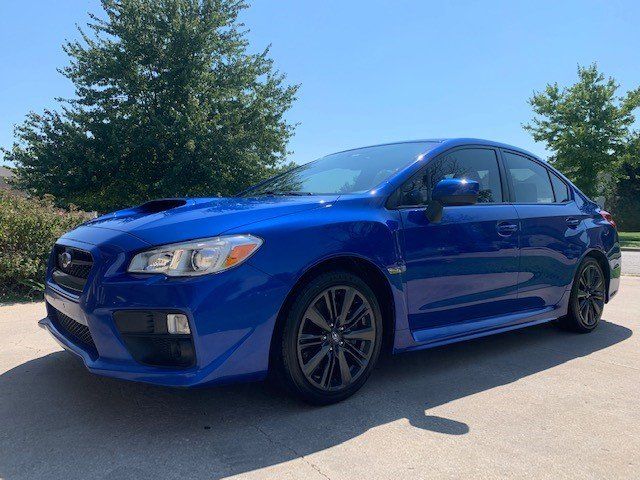 A blue subaru wrx sti is parked in a driveway.