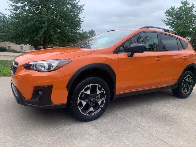 An orange subaru crosstrek is parked in a driveway.