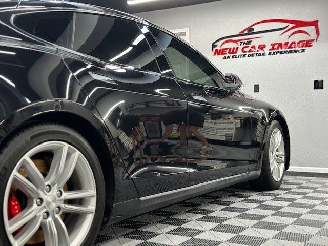 A black car is parked in front of a sign that says new car image