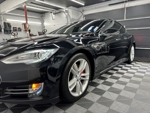 A black tesla model s is parked in a garage.