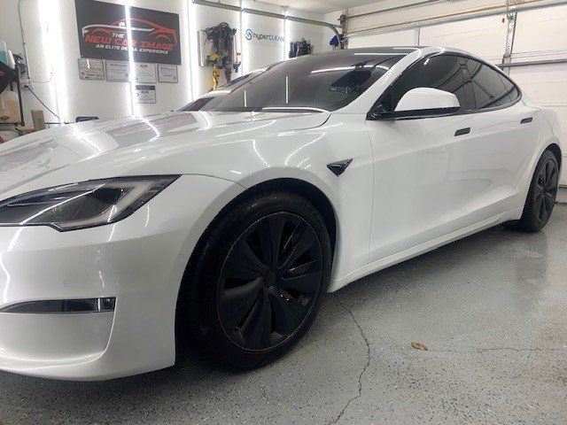 A white tesla model s is parked in a garage.