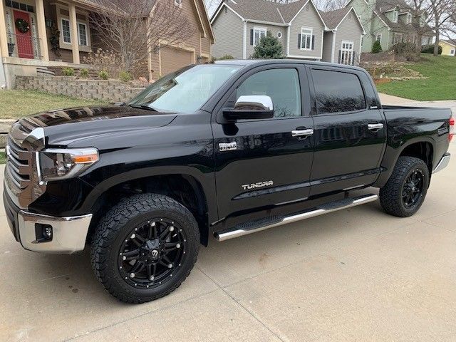 A black toyota tundra is parked in a driveway in front of a house.