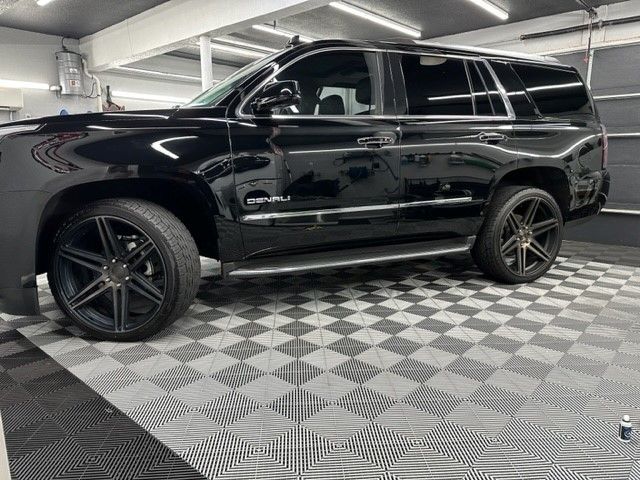 A black suv is parked in a garage on a checkered floor.
