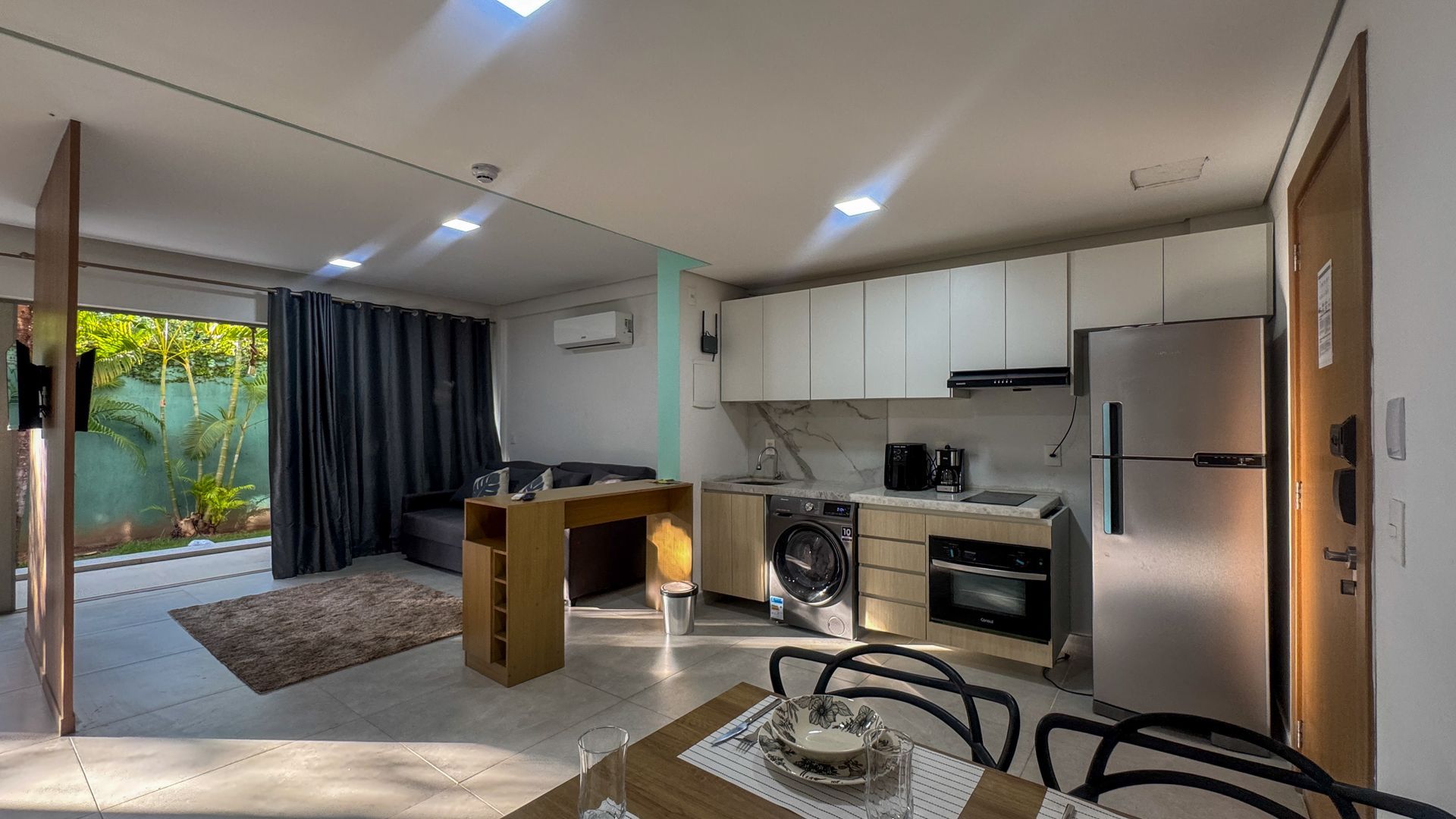 Interior de um pequeno apartamento com cozinha, sala de jantar e sala de estar visíveis.