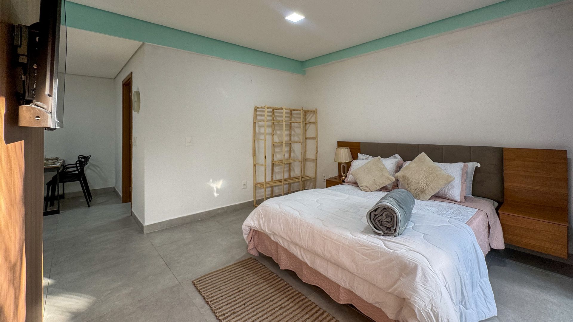 Quarto com cama, cabeceira, tapete e detalhes em azul claro no teto.