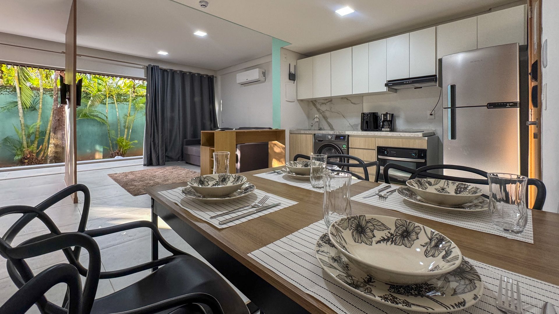 Sala de jantar com mesa para quatro pessoas, integrada à cozinha e com um pátio externo.