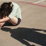 girl siting on ground with a shadow of a man