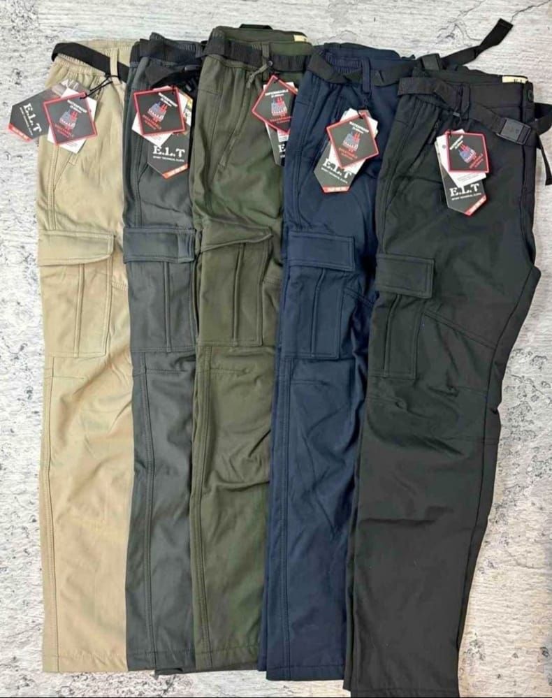 Un grupo de pantalones cargo están apilados uno encima del otro sobre una mesa.