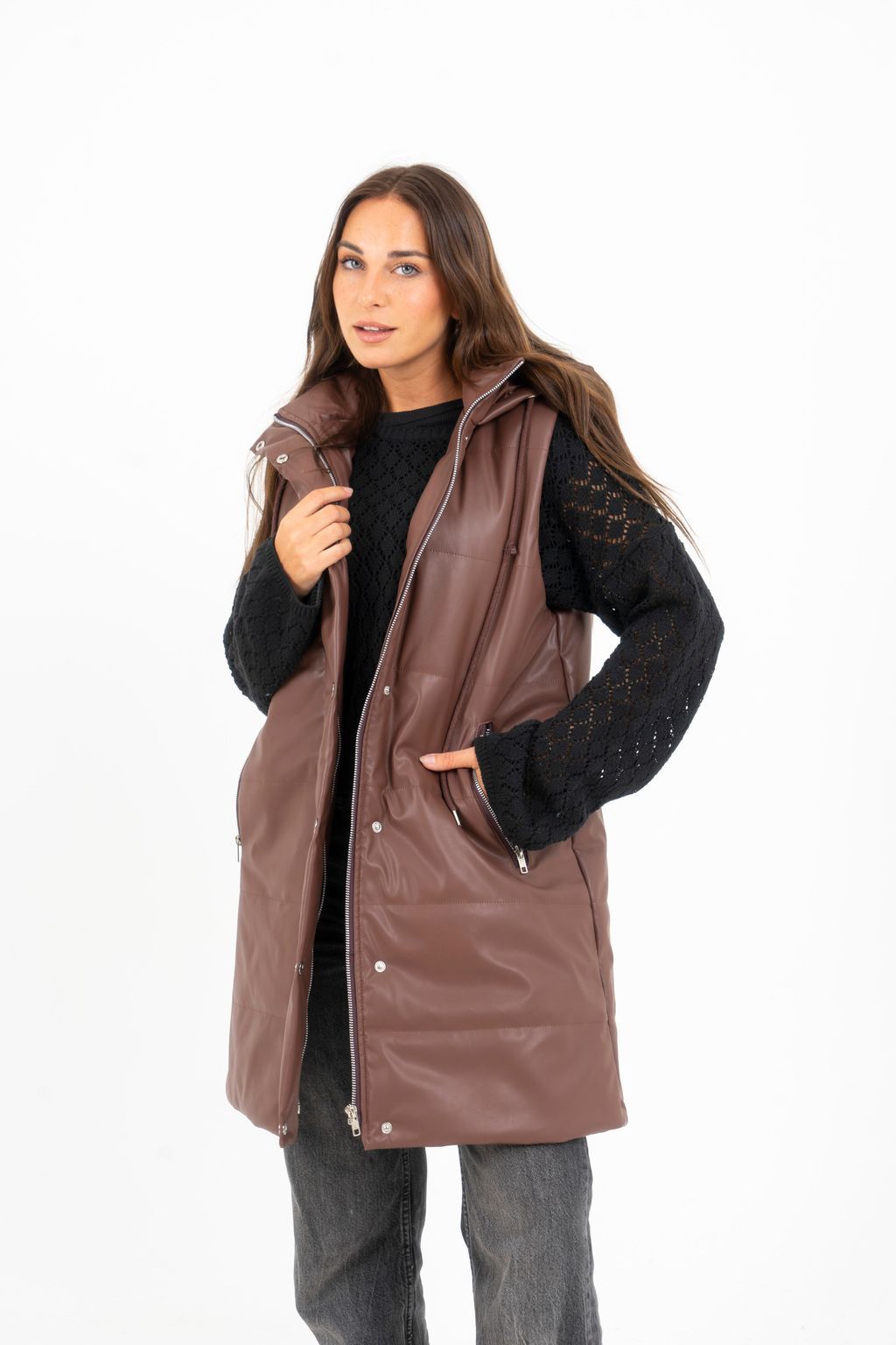 Una mujer lleva un chaleco de cuero marrón y un suéter negro.