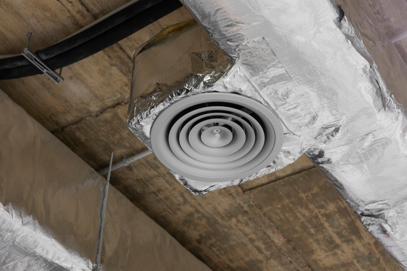 A white air vent is hanging from the ceiling of a building.