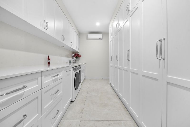 A Laundry Room White Cabinetry and Tiled Floors — Custom Cabinets Design in Winnellie, NT