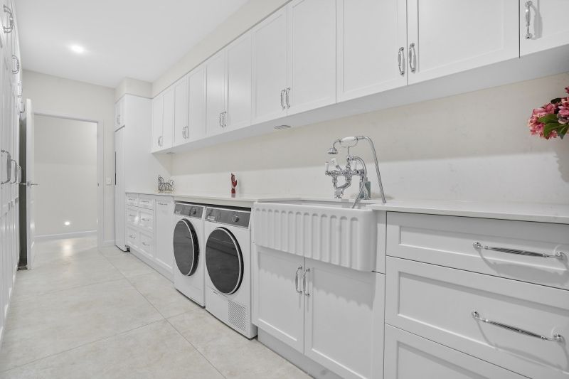 A Laundry Room With Two Washing Machines and a Sink — Custom Cabinets Design in Virginia, NT
