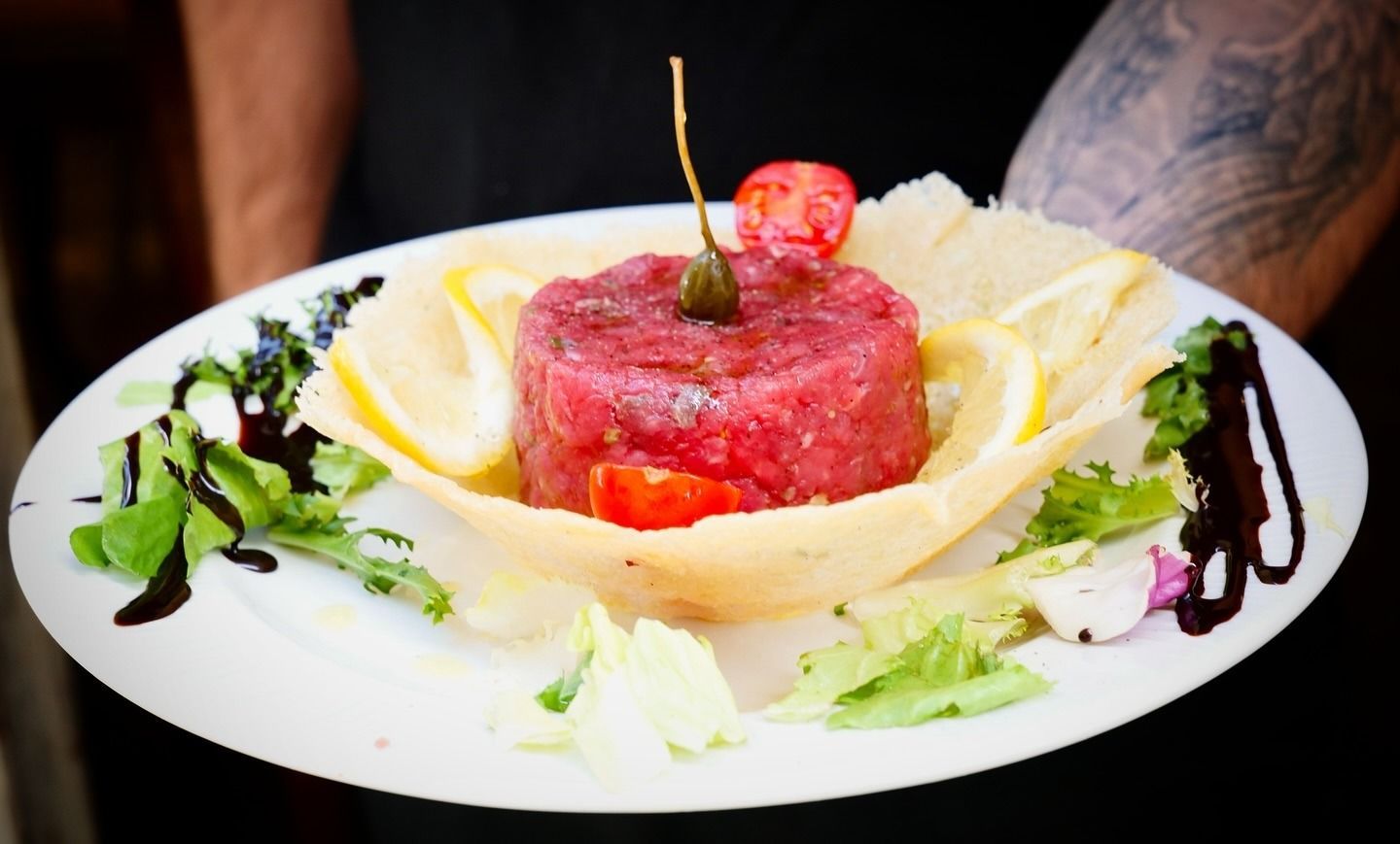 Piatto di tartare di carne cruda con guarnizioni e fette di limone. Servito da una persona.
