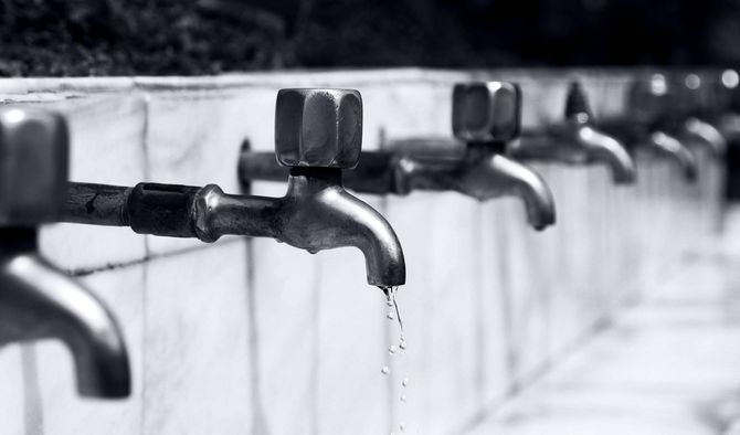 A black and white photo of a row of water faucets.