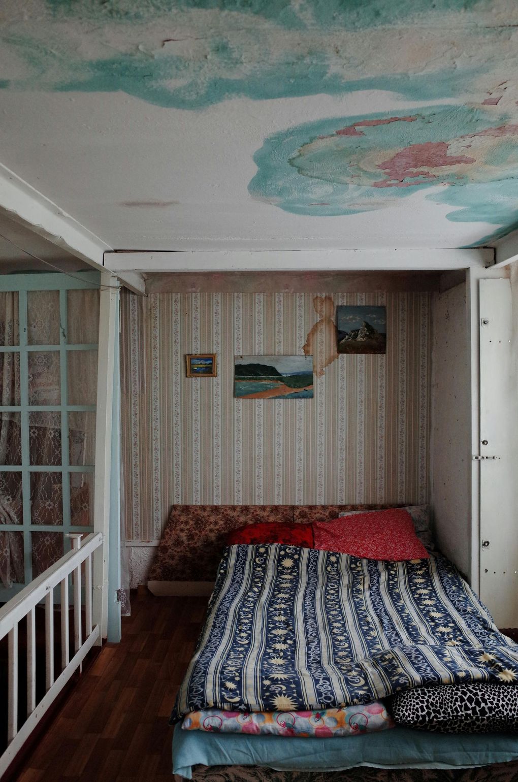 A bedroom with a bed and a painting on the ceiling.