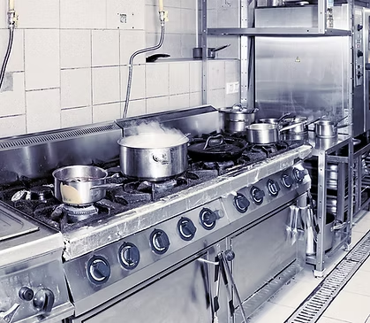 A commercial stainless steel stove in a kitchen with pots cooking on burners.
