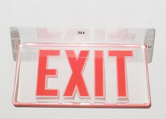 A rectangular red and clear edge-lit EXIT sign mounted on a plain white wall.