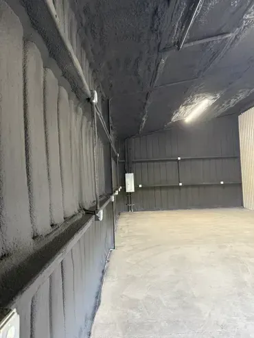 Black insulated warehouse interior with conduit and concrete floor.