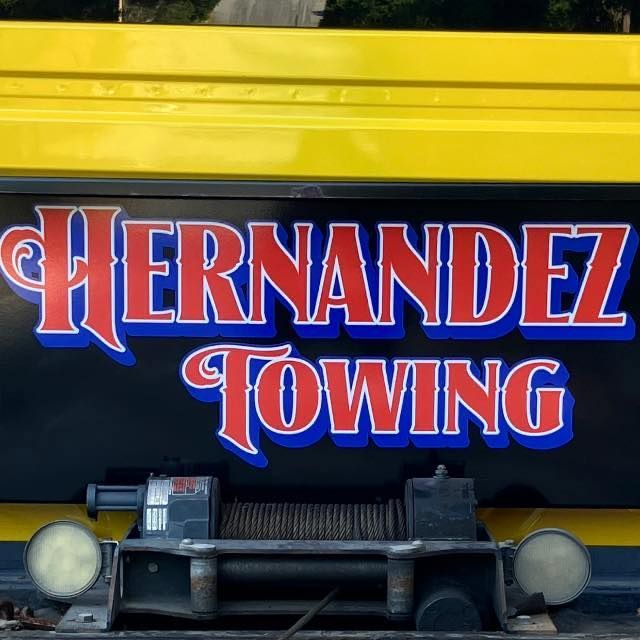 Hernandez Towing logo on a yellow and black tow truck. Red text with blue and white accents.
