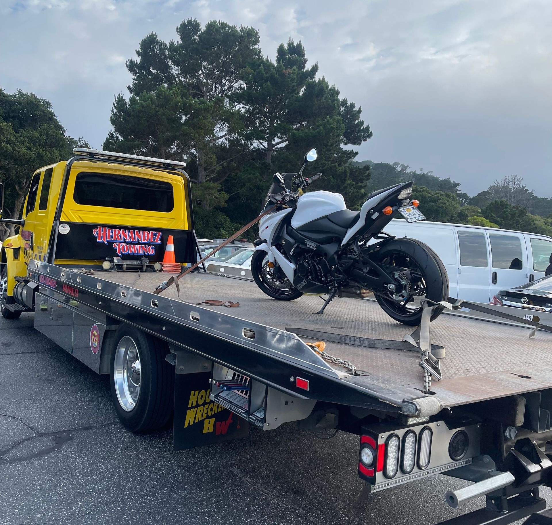Man in orange vest securing car to a tow truck.