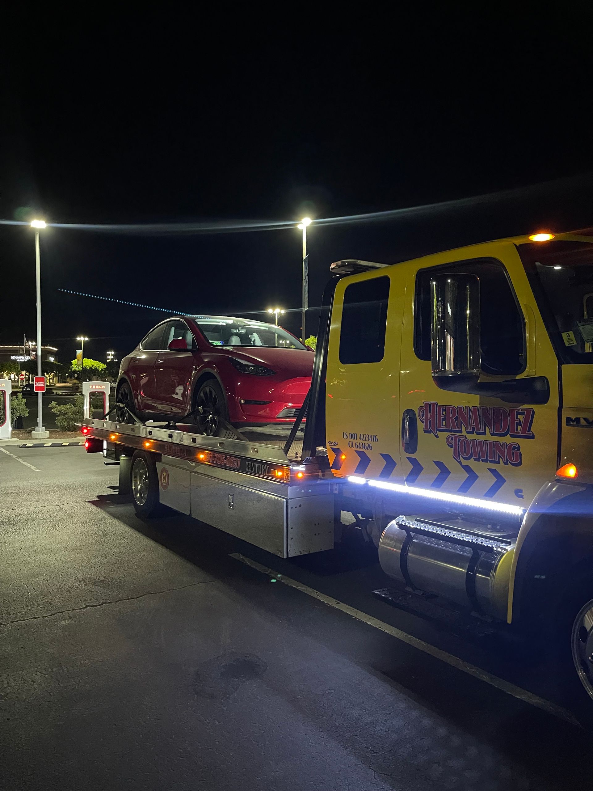 White van with front-end damage being towed onto a flatbed tow truck.