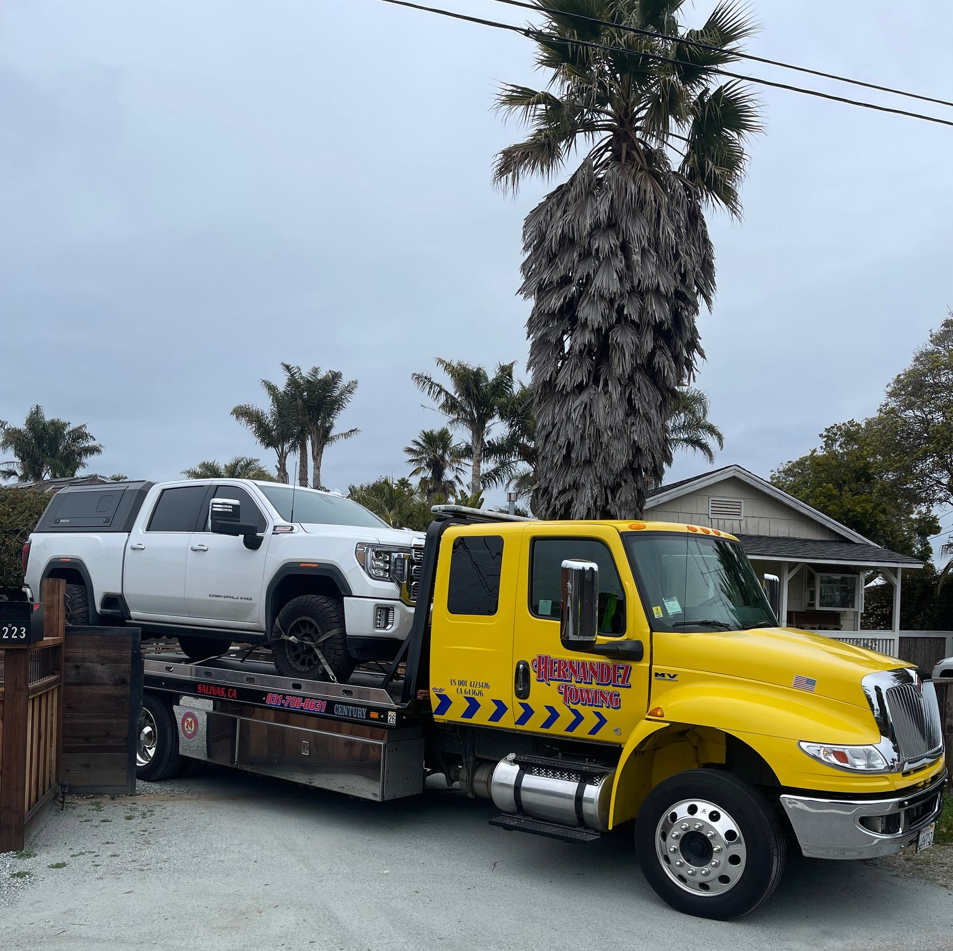 Blue car being towed onto a flatbed tow truck in a garage.